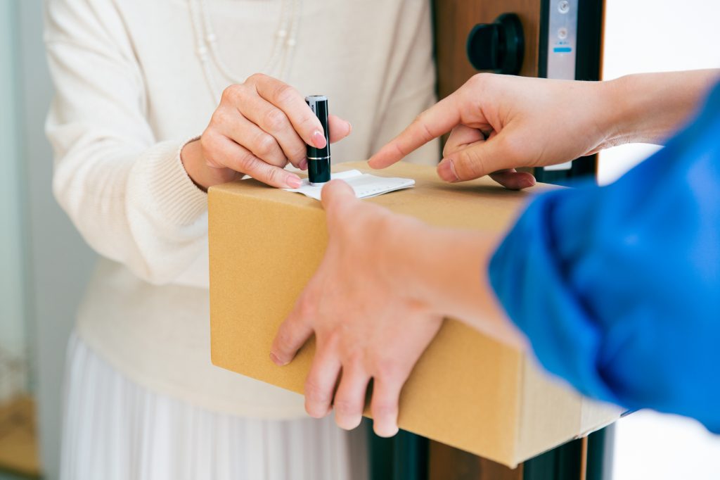 荷物の受け取り伝票にシャチハタを押す女性