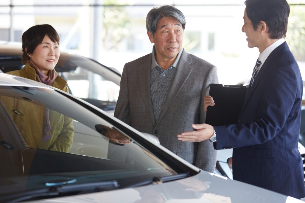 自動車販売店で車を見ている夫婦